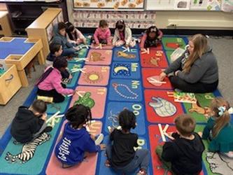 Students are on the carpet with their teacher